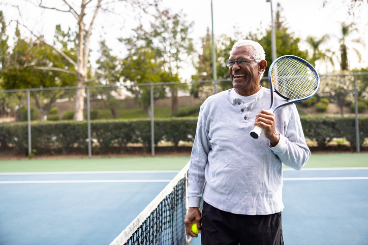 senior man holding a tennis racquet while standing on a tennis court
